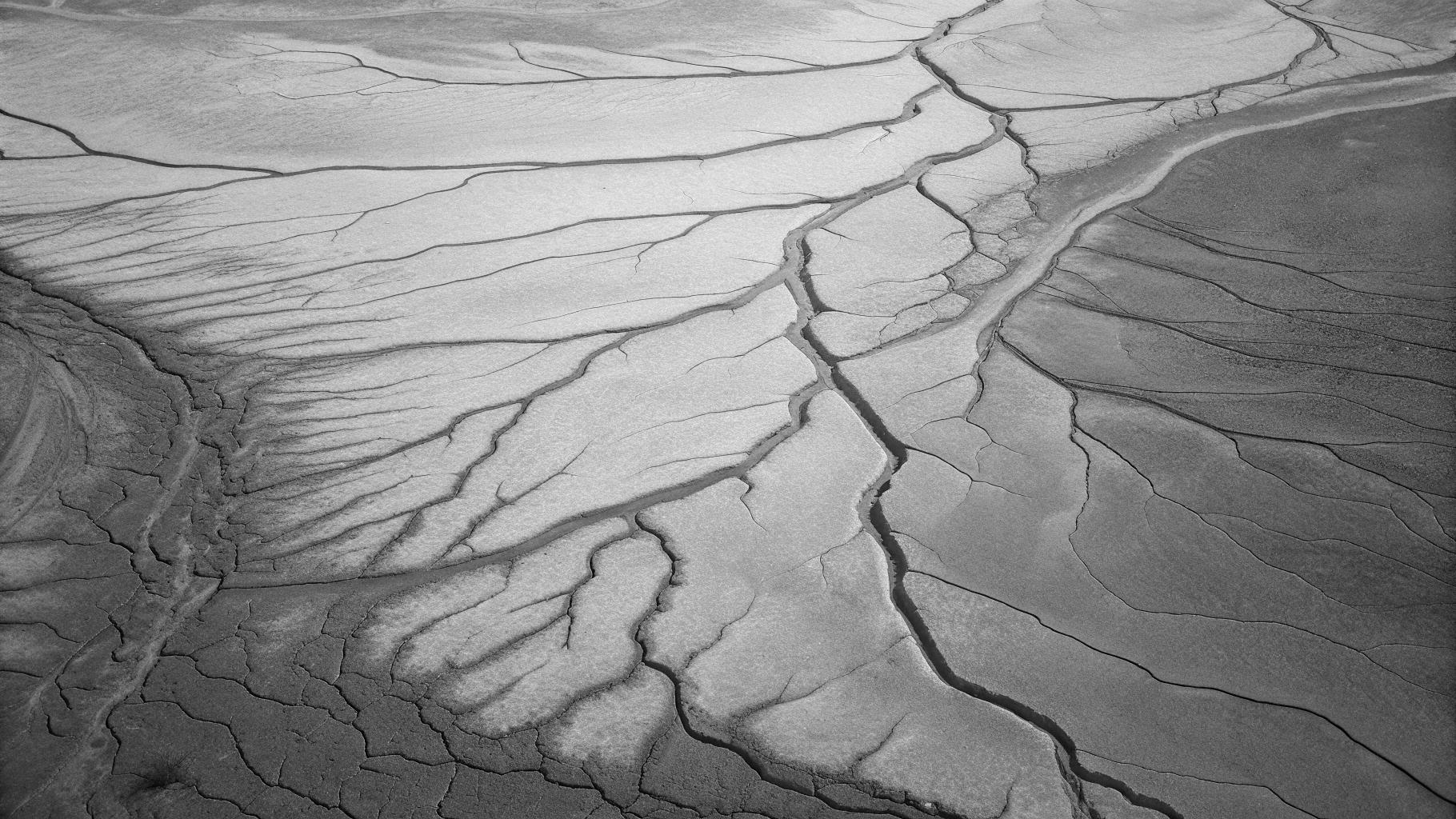 Illustration abstraite d’un réseau de petits cours d’eau asséchés sur un fond de sol craquelé