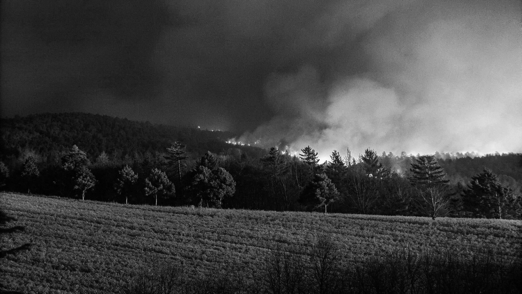 Paysage de massif forestier méditerranéen avec fumée dense et intervention de secours, sans personnes identifiables
