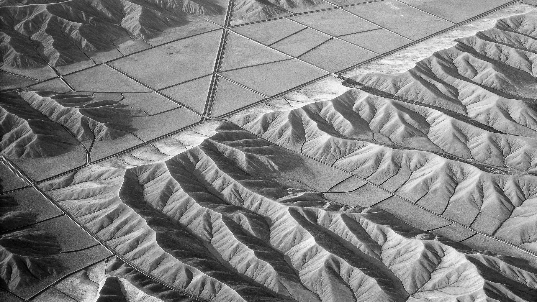 Illustration abstraite de contours de terres fragmentées en tons terreux, avec des lignes géométriques suggérant une division territoriale, sans texte, sans logo, sans visage reconnaissable, format paysage 3:2