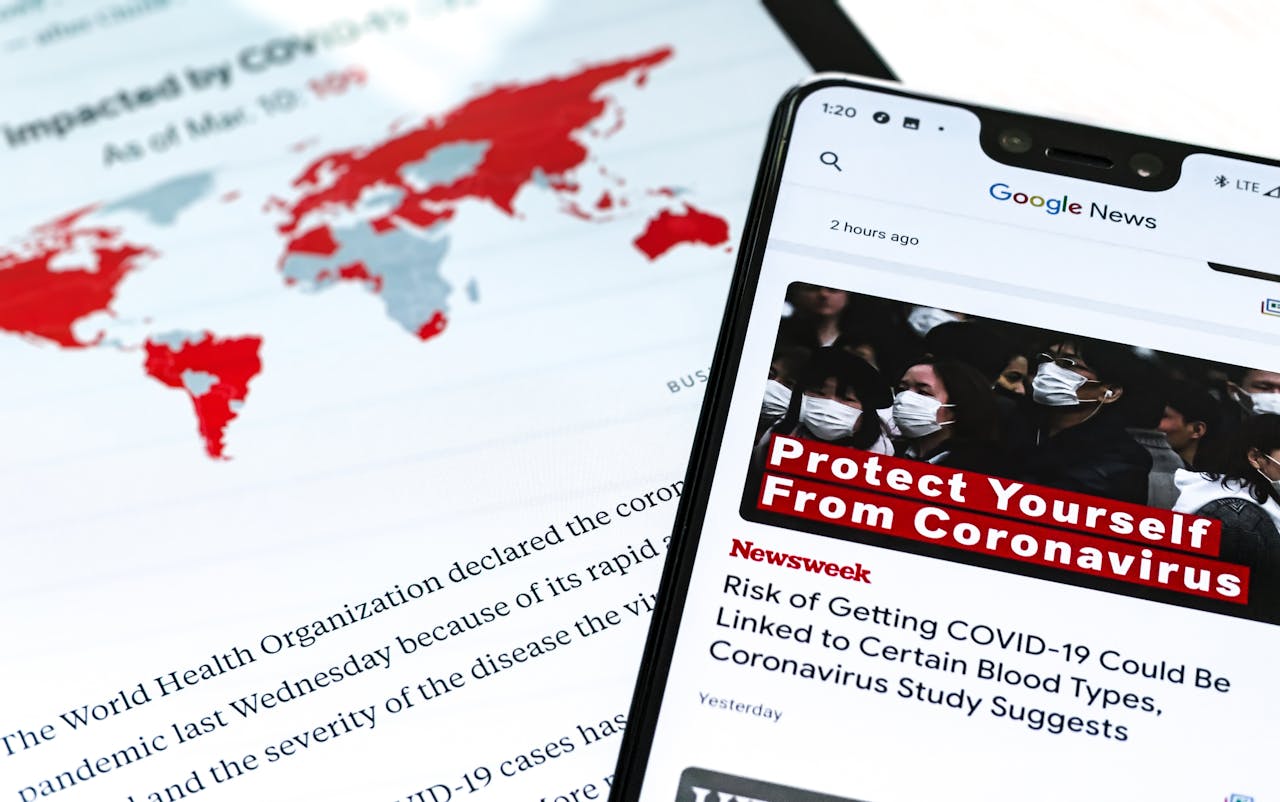 services-01 Smartphone with coronavirus updates and world map showing the impact of COVID-19.