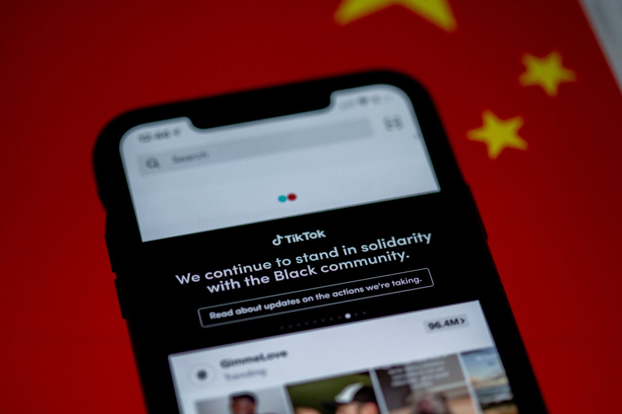 why-choose-us Close-up of a smartphone with TikTok app displayed against a China flag backdrop, highlighting solidarity message.