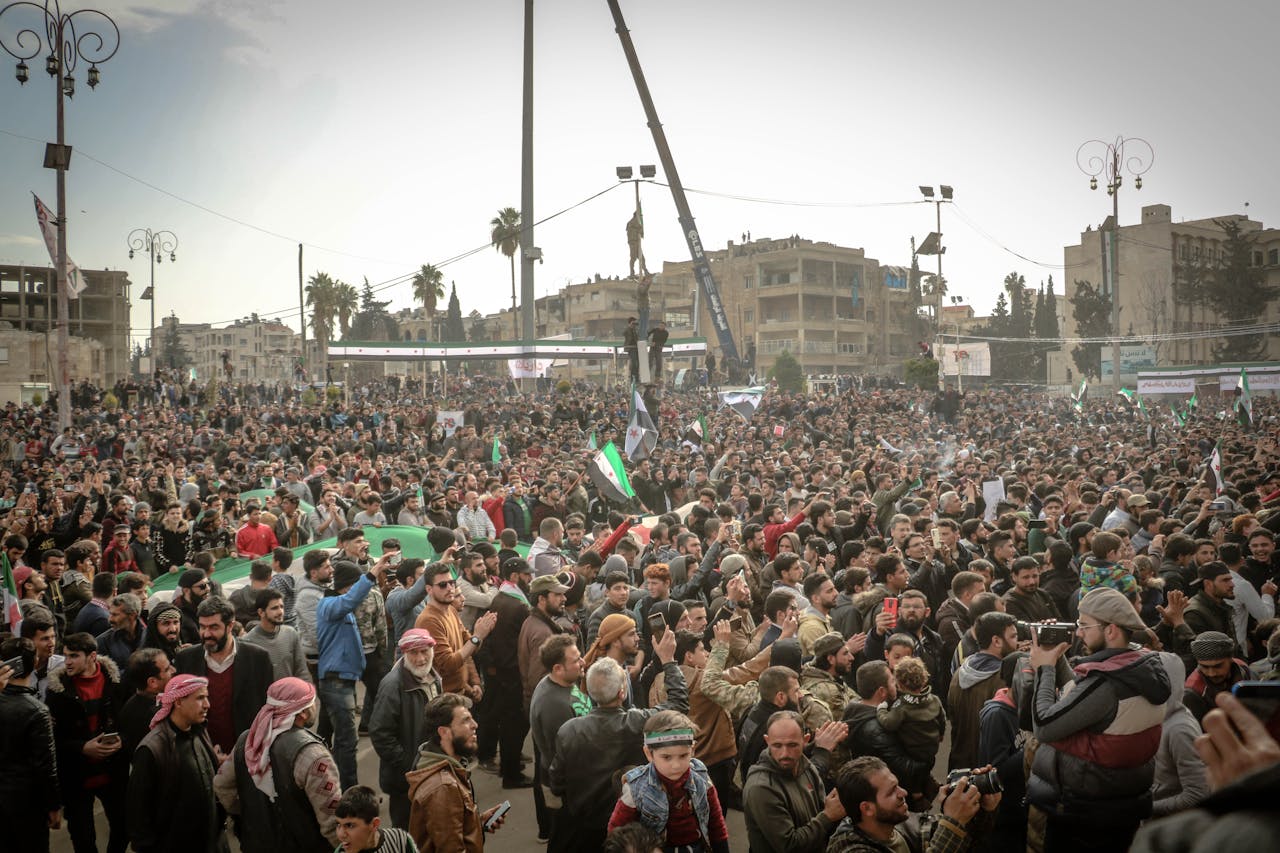 services-02 Large crowd protesting in Idlib, Syria, showcasing unity and activism under cloudy skies.